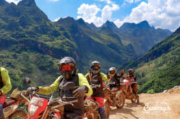Group of dirt bike riders wearing helmets and protective gear on a rocky mountain trail.